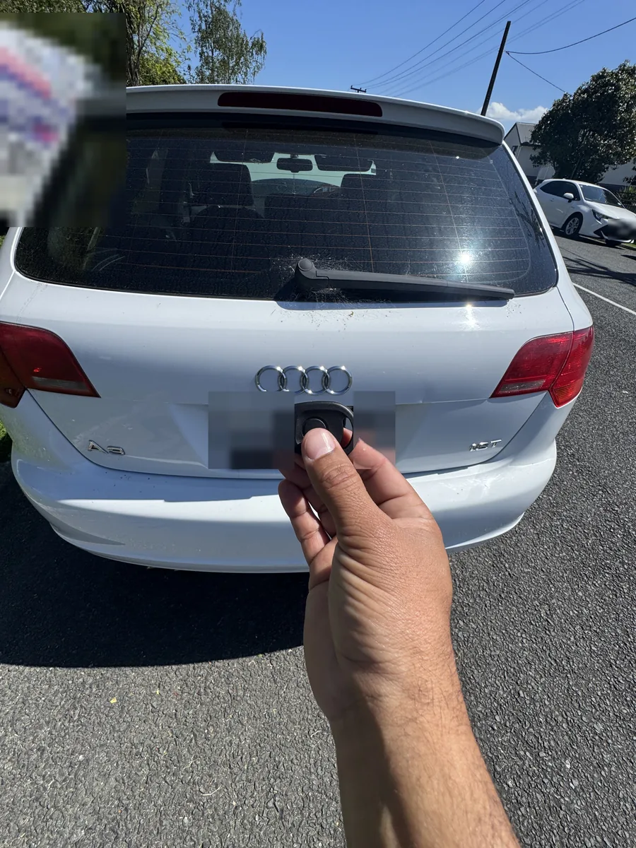 White Audi A3 from behind with the new key held up