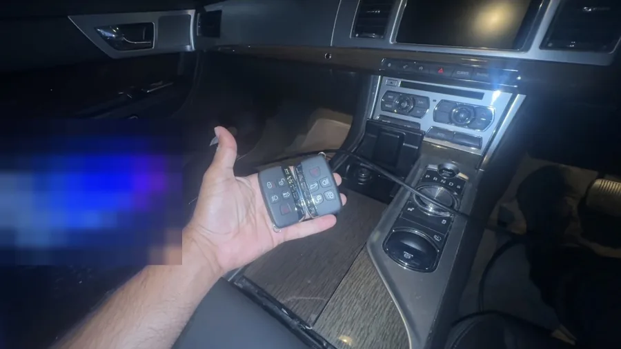 Two Jaguar XF smart keys held up inside the car with a laptop connected to it