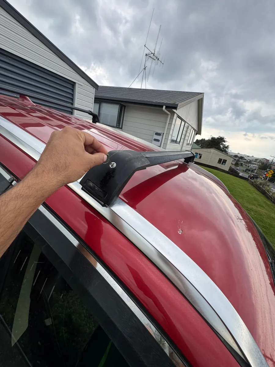 Roof rack key in the lock on the roof bar of a red Mitsubishi Outlander