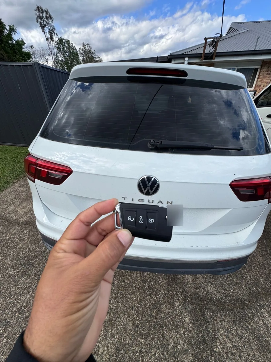 White Tiguan from behind with the new flip key held up
